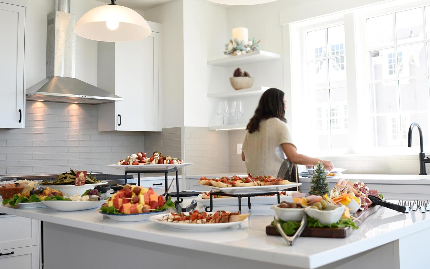 Woman in kitchen with holiday appetizers on counter for a blog about holiday hosting at depoe hills